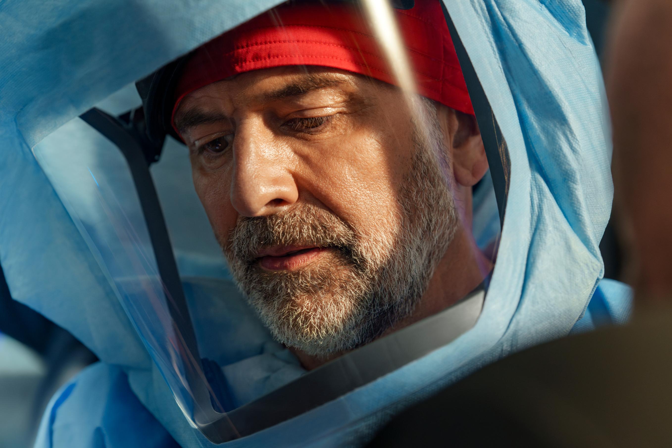Man in full personal protective equipment looking down focused on task.