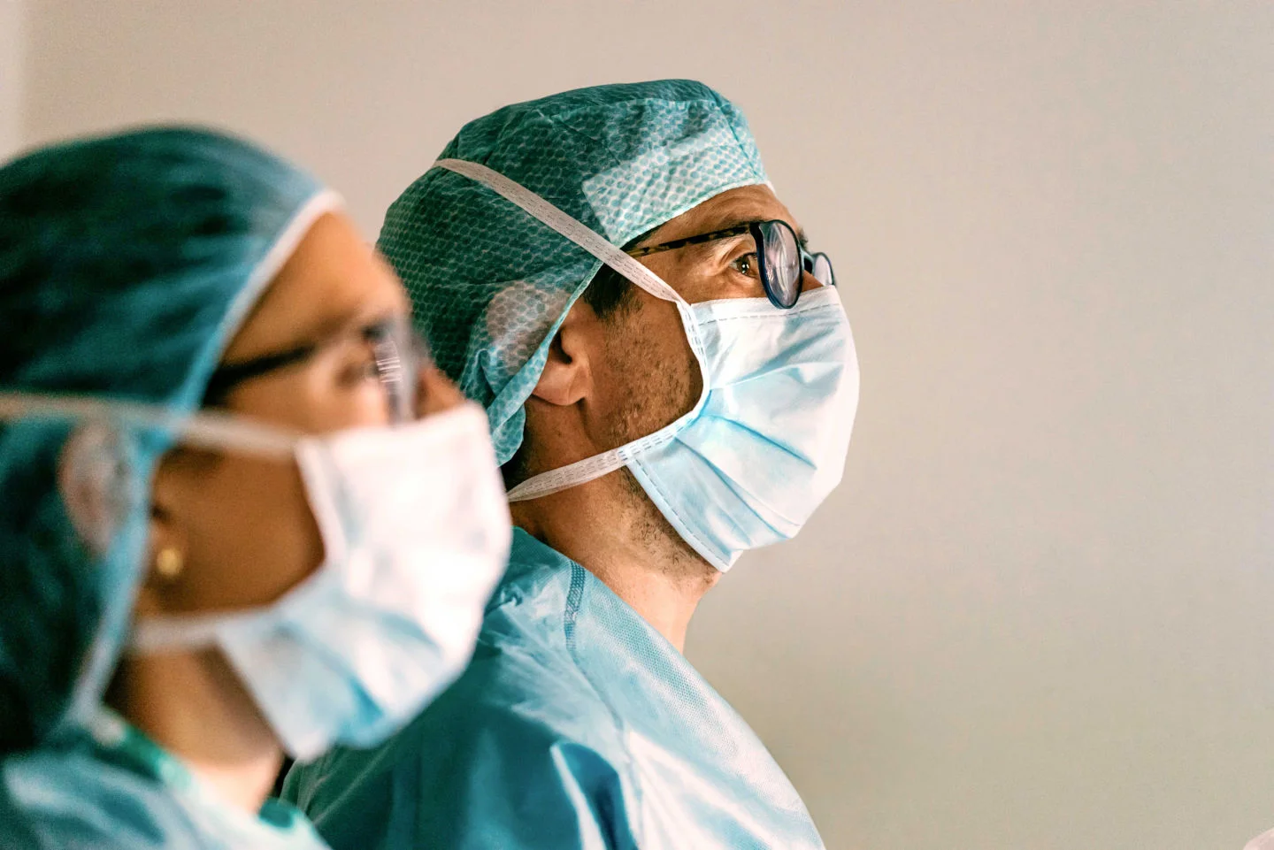 Close up headshot of two masked, Latino physicians looking optimistically into the distance.