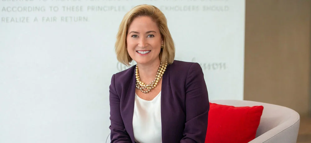 Head and shoulders portrait of Ashley McEvoy, Executive Vice President Worldwide and Chairman of J&J Med Tech seated on a beige chair with a red cushion.